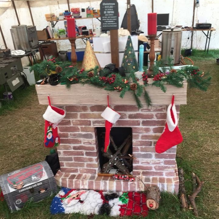 A photo of a chimney piece set up in a tent, decorate for Christmas