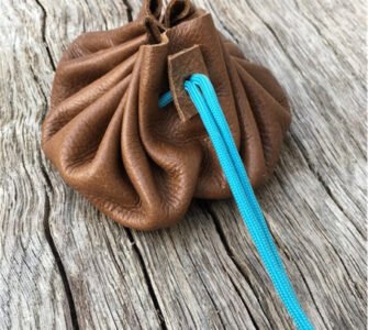 A brown leather pouch with a blue paracord tie holding it closed