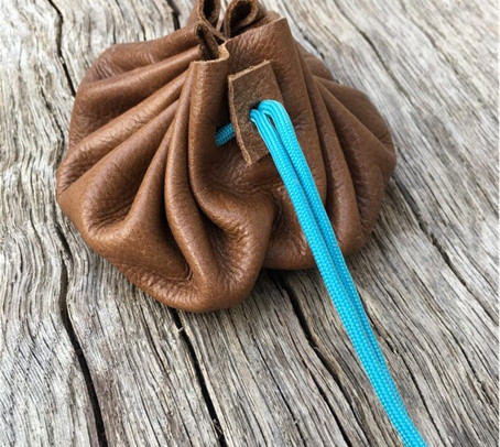 A brown leather pouch with a blue paracord tie holding it closed