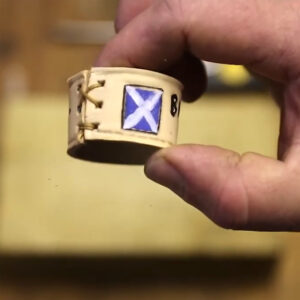 A close up photo of a home made leather woggle decorated with a Scottish flag